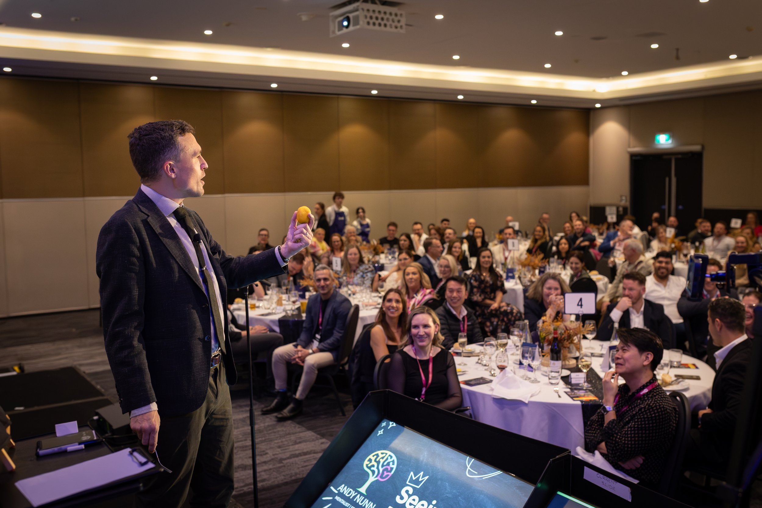 Andy Nunn addressing guests around tables at a corporate event