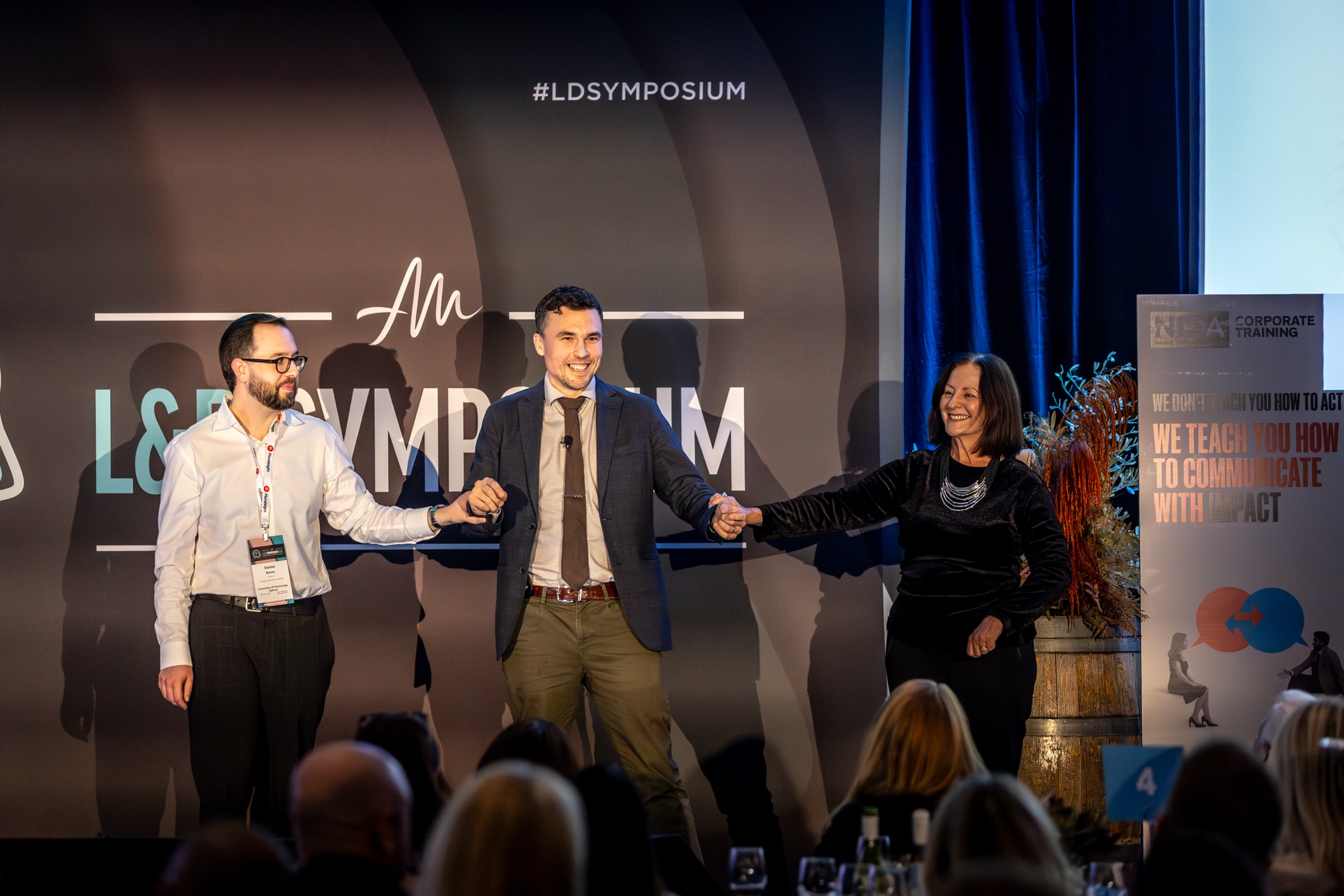Andy Nunn standing between volunteers during an L&D Symposium performance