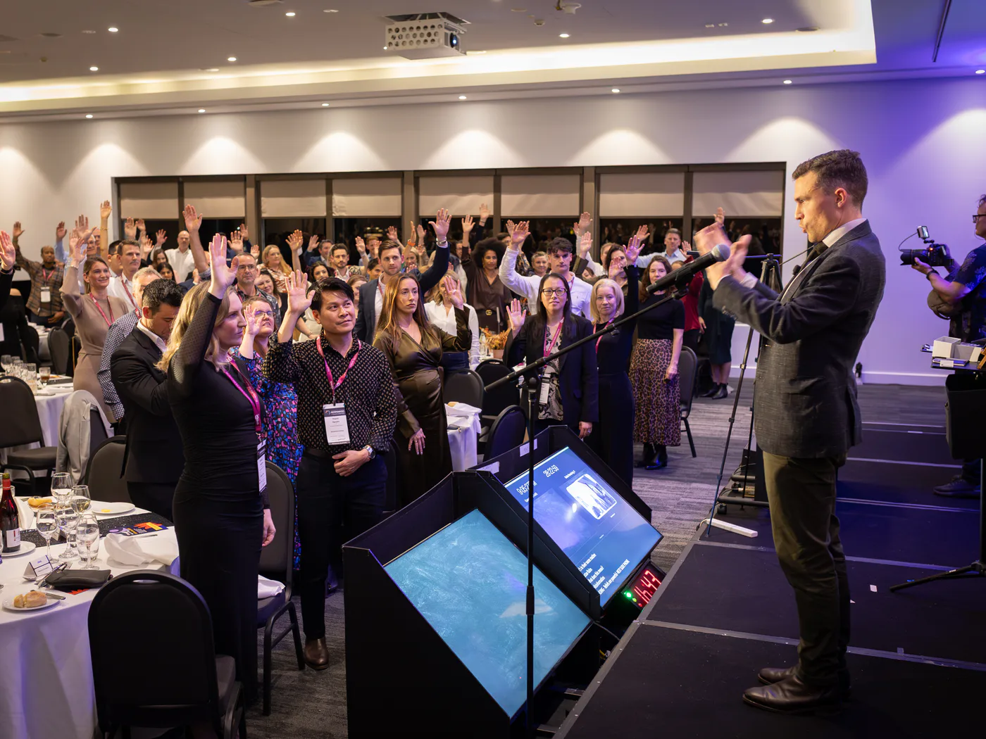 Conference audience raising their hands during an interactive leadership speaker Sydney keynote