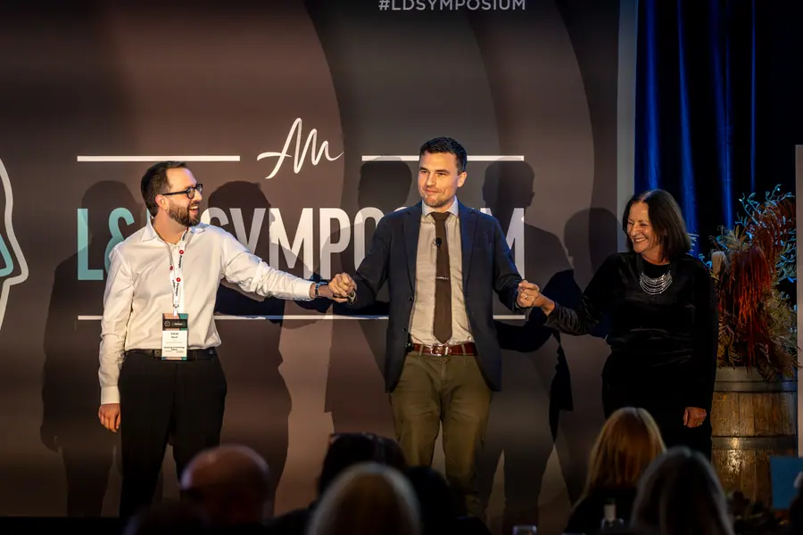 Two smiling participants joining Andy Nunn on stage at a Sydney corporate event